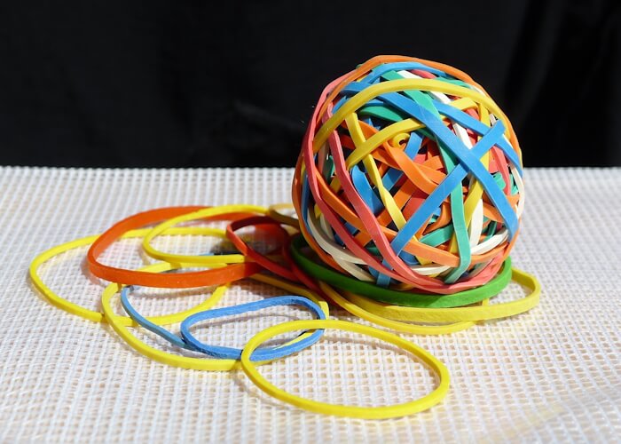 Colorful rubber band ball with loose rubber bands around it.